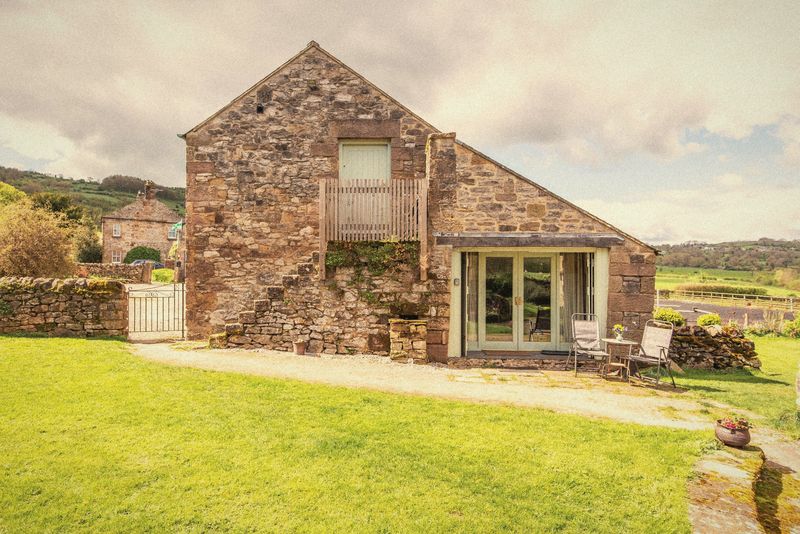The Forge, a stone barn with patio doors and a lawn