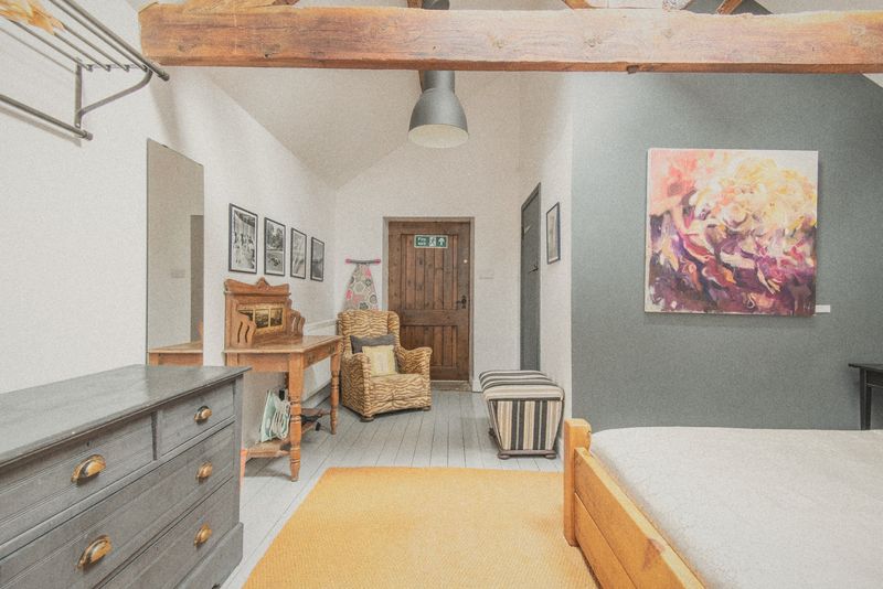 The bedroom with wooden bed and orange throw