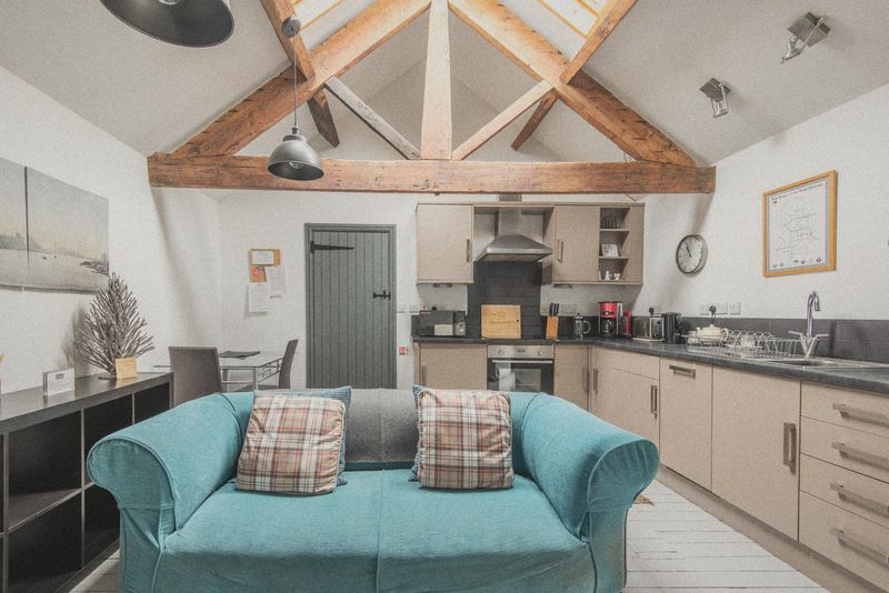 The Hayloft’s vaulted lounge with teal settee and beams