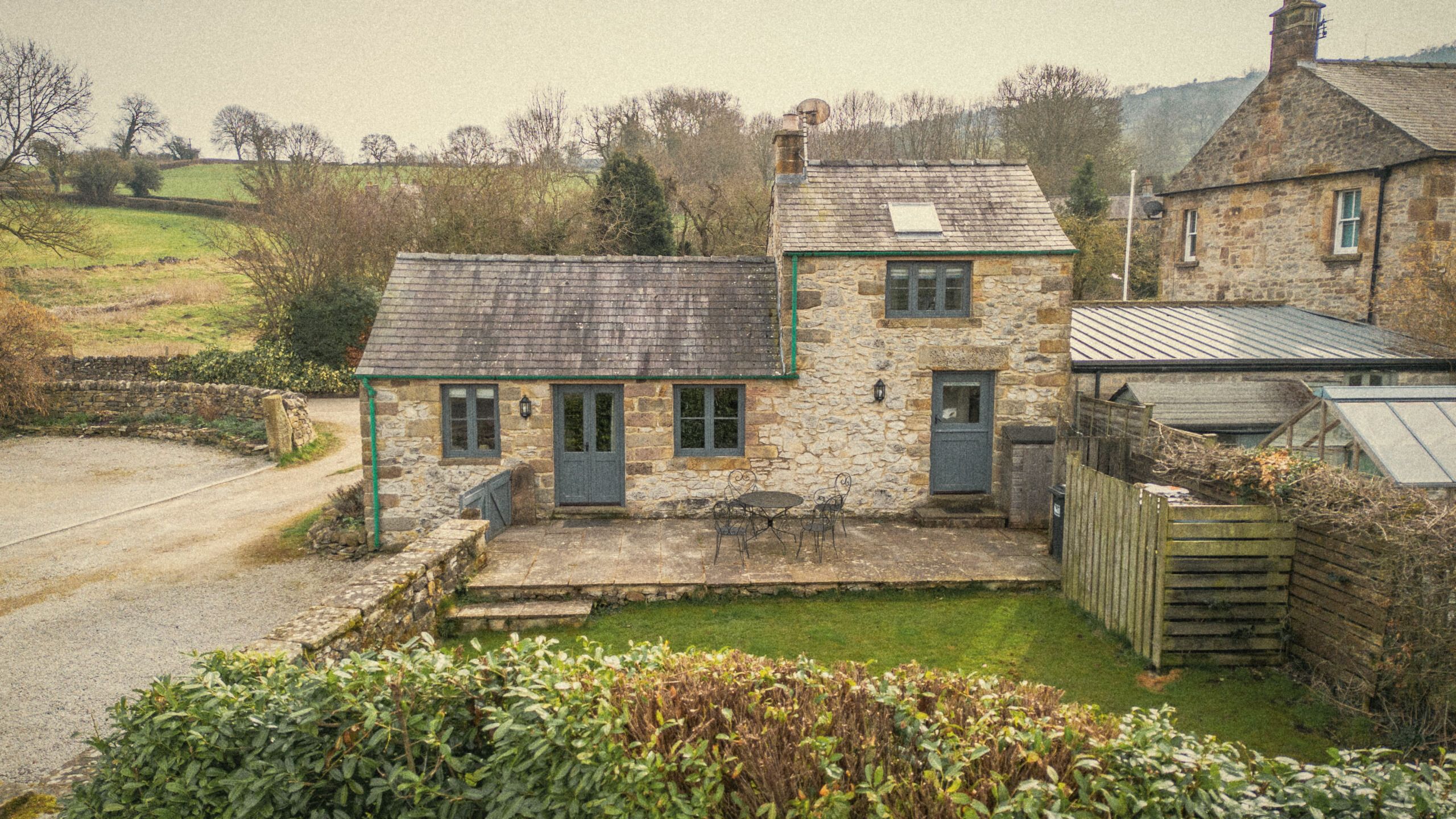 Thistledown Cottage, a stone cottage with a sunny patio, table and chairs