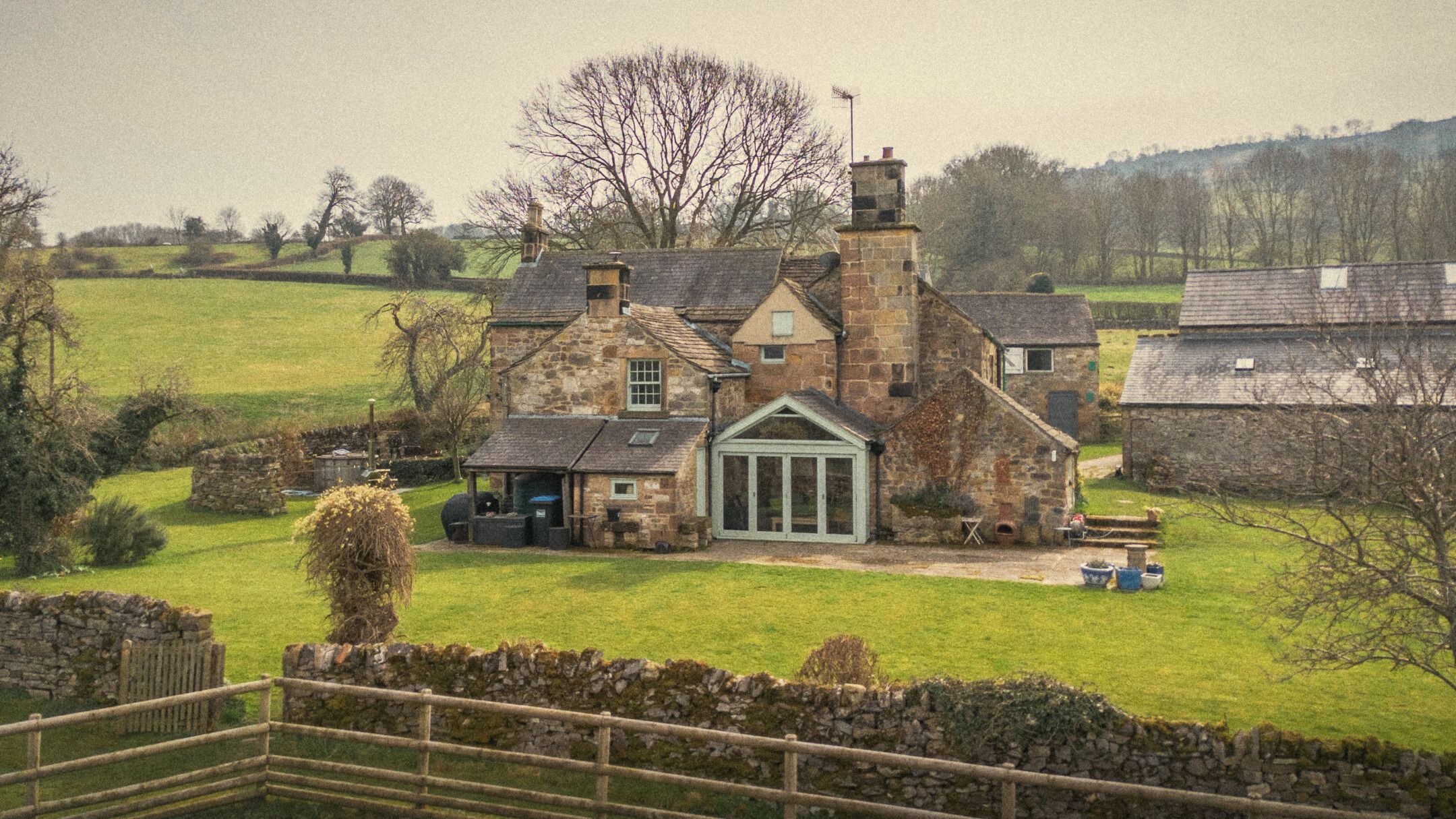 The back of the house with its conservatory, lawn and stone walls