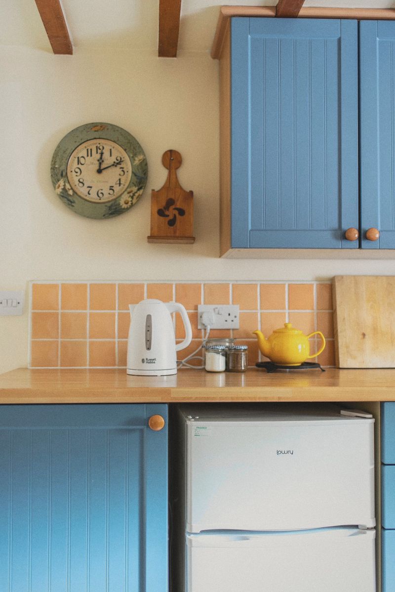 Blue kitchen units and a wall clock in the dining kitchen
