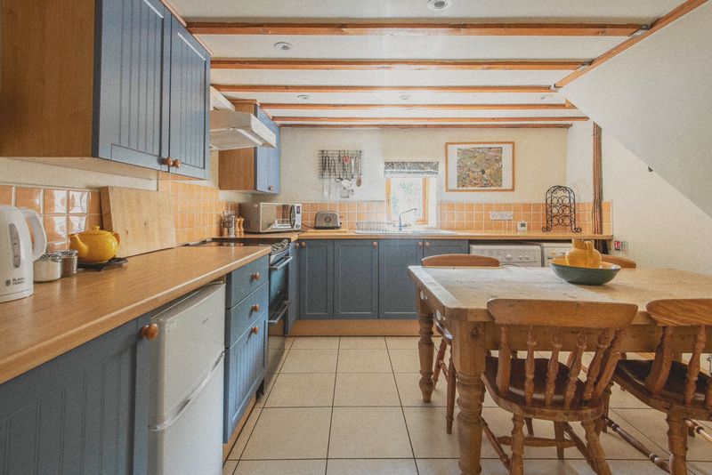The dining kitchen with blue units, pine table and beams