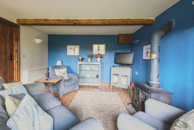 The beamed sitting room with grey settees and log burner