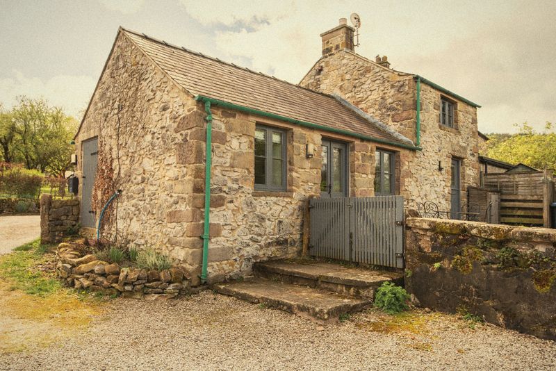 The cottage’s stone steps and green door beside the yard